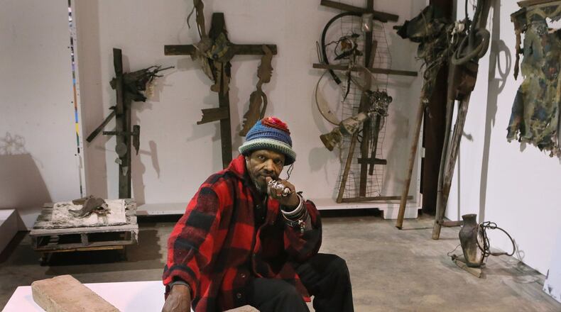 Artist Lonnie Holley, who recently moved to Atlanta, in collector William Arnett’s warehouse, which contains some of Holley’s artworks including this granite construction called “Mith.” BOB ANDRES / BANDRES@AJC.COM