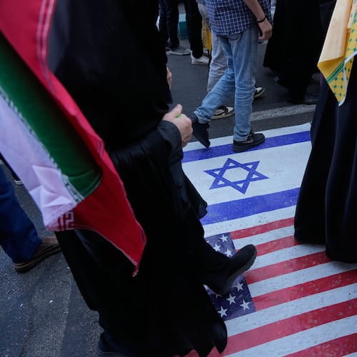 Demonstrators walk on a representation of the U.S. and Israeli flags during an annual rally in front of the former U.S. Embassy in Tehran, celebrating the anniversary of the 1979 takeover of the embassy, Iran, Tuesday, Nov. 4, 2025. (AP Photo/Vahid Salemi)