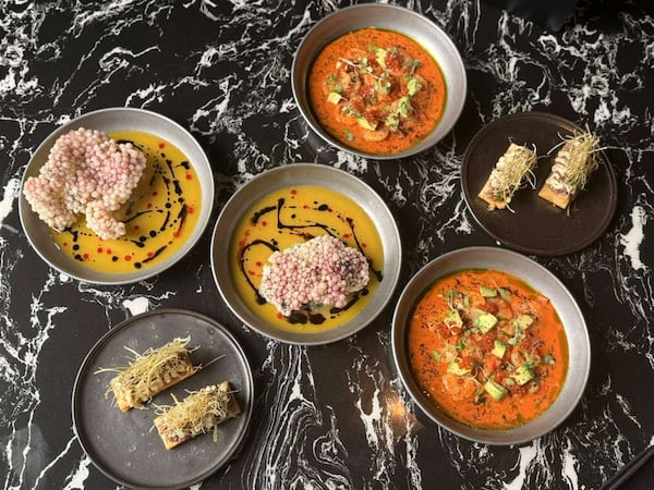 Six plates sit on a marbled table with dishes from the forthcoming Latin restaurant, Botánico Cocina & Social Club. The dishes bright orange sea bass ceviche and crunchy tapioca crackers.