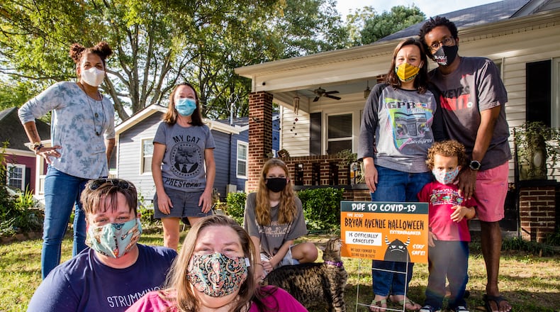 The East Point neighborhood around Bryan Avenue replaces Halloween decorations with yard signs announcing the 2020 extravaganza is canceled. The close-knit community includes Shannon Korta, from top left, Joann Richardson, Reagan Fizell; the Hackshaw family Emmalee, Kevin and 3-year-old Elliott; with Andria Towne, front left, and Sheila Merritt. Jenni Girtman for The AJC