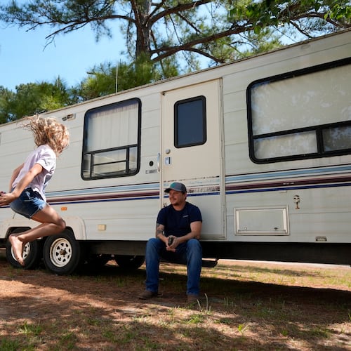 Annabelle Enke plays outside a camper Friday as Michael Gibson looks on in Nahunta, Georgia, after the Enke family lost their home in the Brantley Highway 82 fire earlier this week. (Mike Stewart/AP)