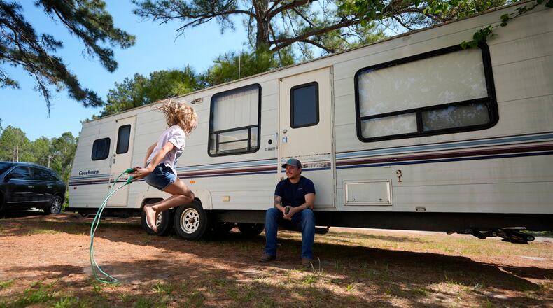 Annabelle Enke plays outside a camper Friday as Michael Gibson looks on in Nahunta, Georgia, after the Enke family lost their home in the Brantley Highway 82 fire earlier this week. (Mike Stewart/AP)