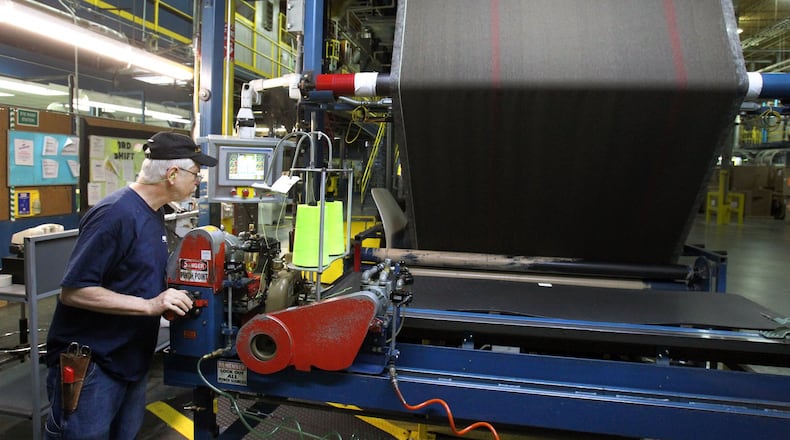 Finishing associate Lyn Mohrman works at the sew-on station on the coater at Shaw Industries Plant 15 in the May 2012 photo. AJC File Photo