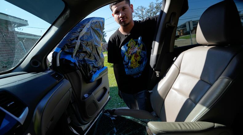 Jonathan Escalante stands over the broken window of his mother's car, which was shattered by federal immigration agents who took her away, during a federal immigration crackdown in Kenner, La., Tuesday, Dec. 9, 2025. (AP Photo/Gerald Herbert)