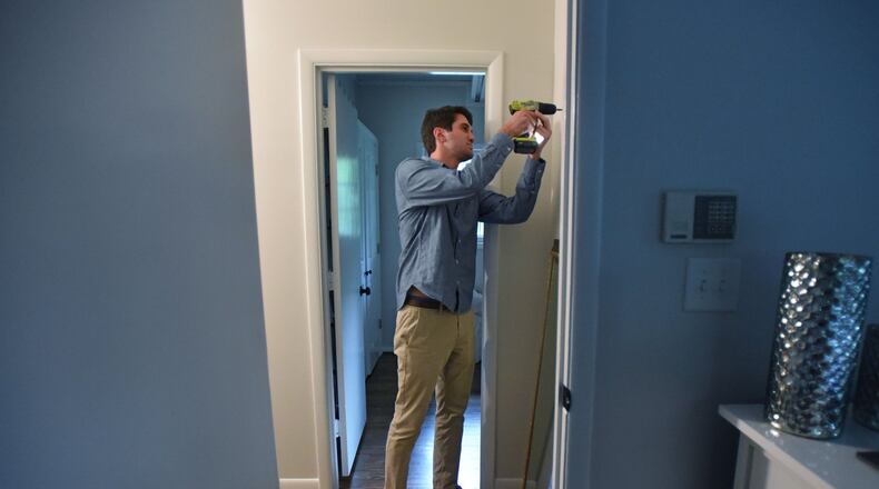 First time home buyer Mark Viglotti prepares to hang a morror at his new home in Brookhaven. HYOSUB SHIN / HSHIN@AJC.COM