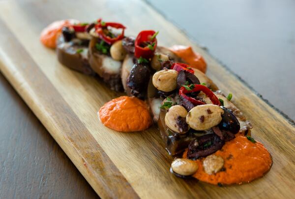 The octopus terrine, a starter at Apron, is served with dollops of Romesco sauce, olives, pickled Fresno peppers and Marcona almonds. CONTRIBUTED BY HENRI HOLLIS