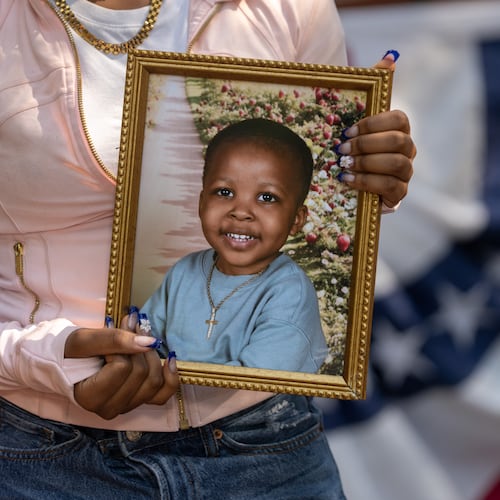 A family member holds a framed photograph of Messiah Harris, a 2-year-old boy found dead in Marietta, during a news conference in Marietta Square on Wednesday, Aug. 12, 2026. (Ben Hendren for the AJC)