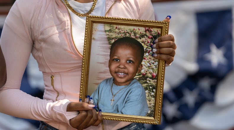 A family member holds a framed photograph of Messiah Harris, a 2-year-old boy found dead in Marietta, during a news conference in Marietta Square on Wednesday, Aug. 12, 2026. (Ben Hendren for the AJC)