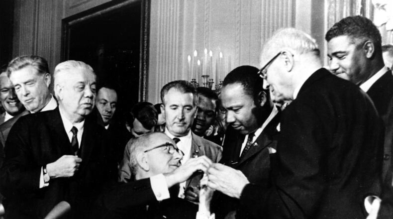 Tuesday marked 60 years since U.S. President Lyndon B. Johnson signed into law the Civil Rights Act of 1964. At the signing ceremony, Johnson reaches to shake hands with the Martin Luther King Jr. after presenting the civil rights leader with one of the 72 pens used to sign the measure. (AP Photo)