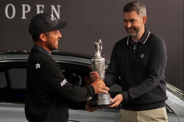 Xander Schauffele of the United States, left, winner of the 2024 British Open, hands back the Claret Jug trophy to the R&A CEO Mark Darbon ahead of the 2025 British Open golf championship at the Royal Portrush Golf Club, Northern Ireland, Monday, July 14, 2025. (AP Photo/Fransisco Seco)