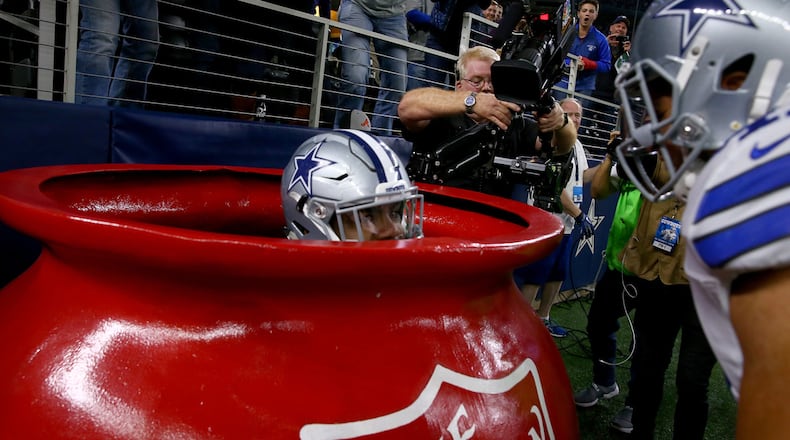 Ezekiel Elliott #21 of the Dallas Cowboys celebrates after scoring a touchdown by jumping into a Salvation Army red kettle during the second quarter against the Tampa Bay Buccaneers at AT&T Stadium on December 18, 2016 in Arlington, Texas.