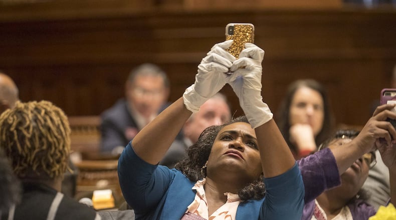 Georgia Rep. Donna McLeod, D - Lawrenceville, takes a photo of the final vote on the House resolution while wearing gloves during a special called session at the Georgia State Capitol Building, Monday, March 16, 2020. (ALYSSA POINTER/ALYSSA.POINTER@AJC.COM)