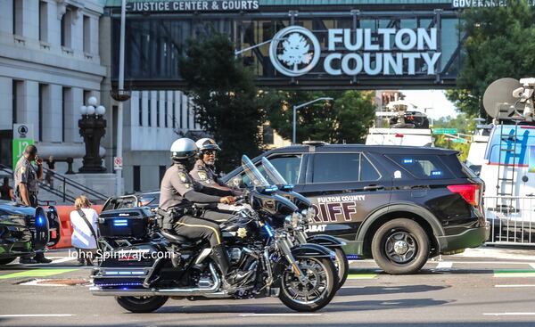 Fulton County sheriff's deputies and a stable of television news crews wait outside the Fulton County courthouse Monday as prosecutors began presenting their election interference case against former President Donald Trump and others.