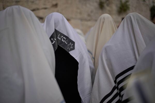 Covered in prayer shawls, Jewish men of the Cohanim Priestly caste participate in a blessing during the holiday of Passover, at the Western Wall, the holiest site where Jews can pray, in the Old City of Jerusalem, Tuesday, April 15, 2025. (AP Photo/Leo Correa)
