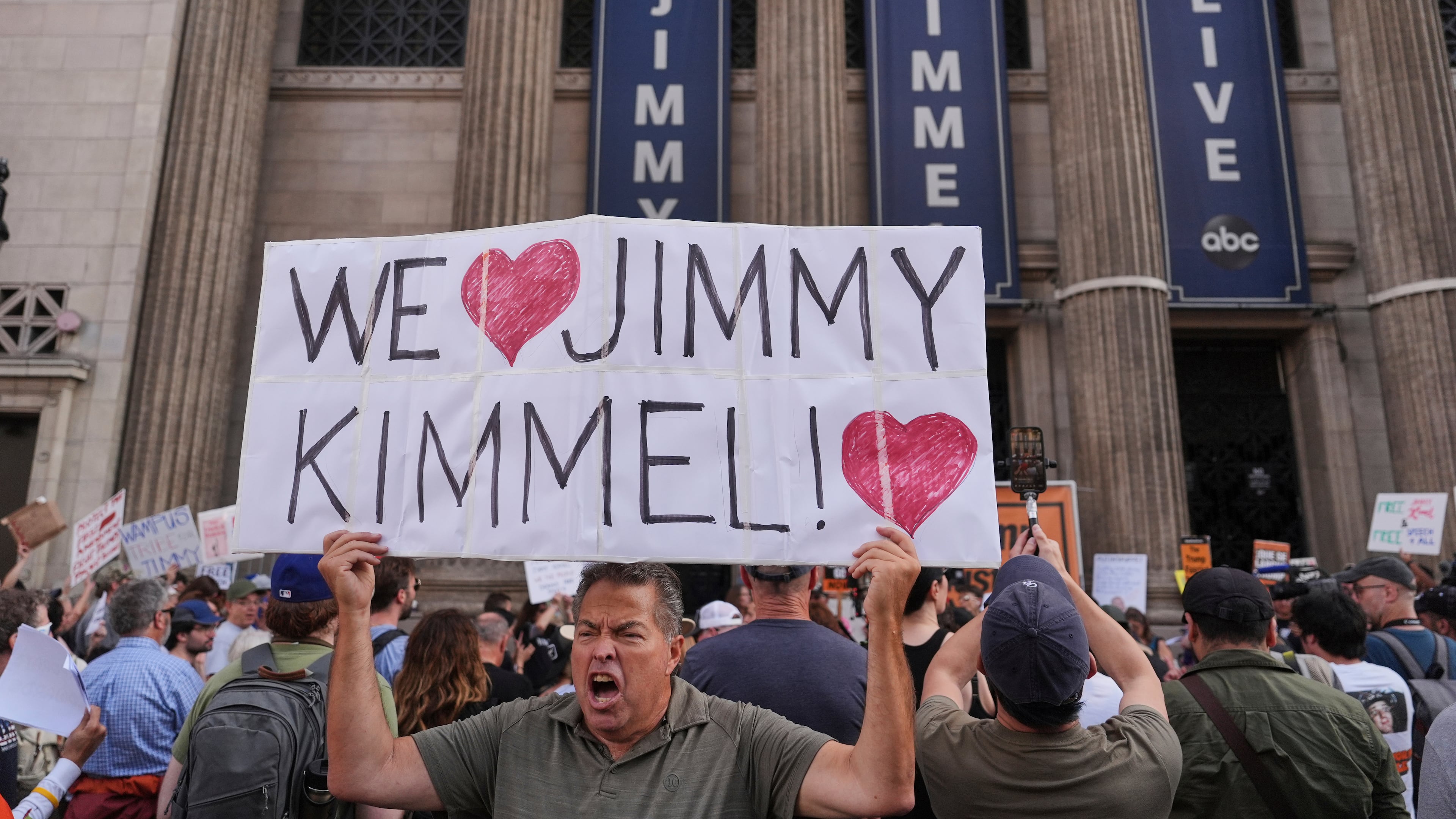 FILE - Oscar Villanueva holds a sign outside El Capitan Entertainment Centre, where the late-night show "Jimmy Kimmel Live!" is staged, Sept. 18, 2025, in Los Angeles. (AP Photo/Jae C. Hong, File)
