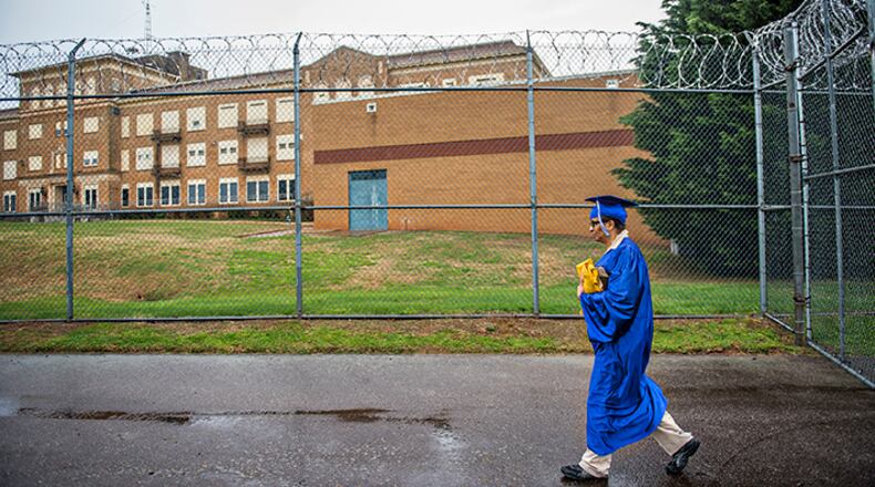 Wearing her cap and gown, Sandra Daniel walks back through security at the Lee Arrendale Correctional Facility in Alto on Friday, April 10, 2015. Daniel is one of 43 inmates to graduate with a certificate in theological studies on Friday at the state prison.