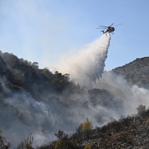 A helicopter drops water on a wildfire on the island of Salamina, west of Athens, Greece, Sunday, Aug. 16, 2026. (AP Photo/Michael Varaklas)