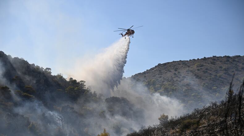A helicopter drops water on a wildfire on the island of Salamina, west of Athens, Greece, Sunday, Aug. 16, 2026. (AP Photo/Michael Varaklas)