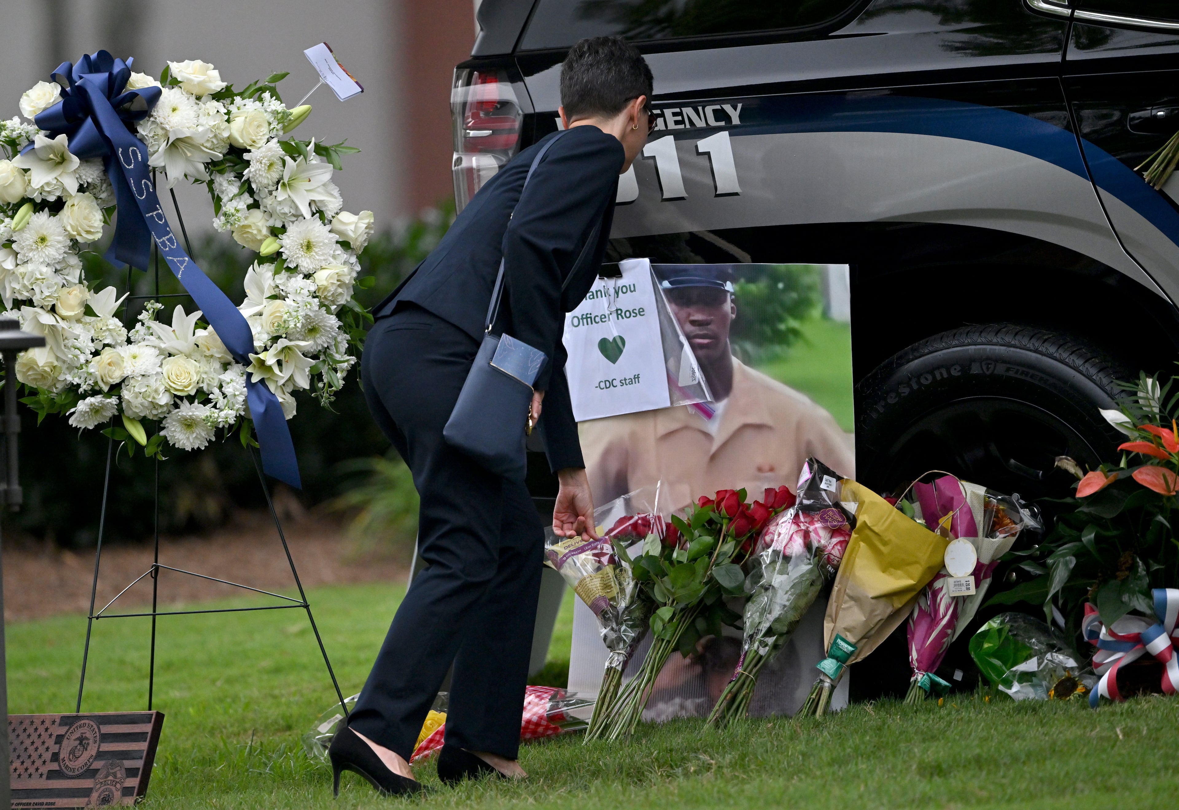 A mourner leaves a flower at a memorial for fallen DeKalb County police Officer David Rose before the memorial service in his honor. (Hyosub Shin/AJC)