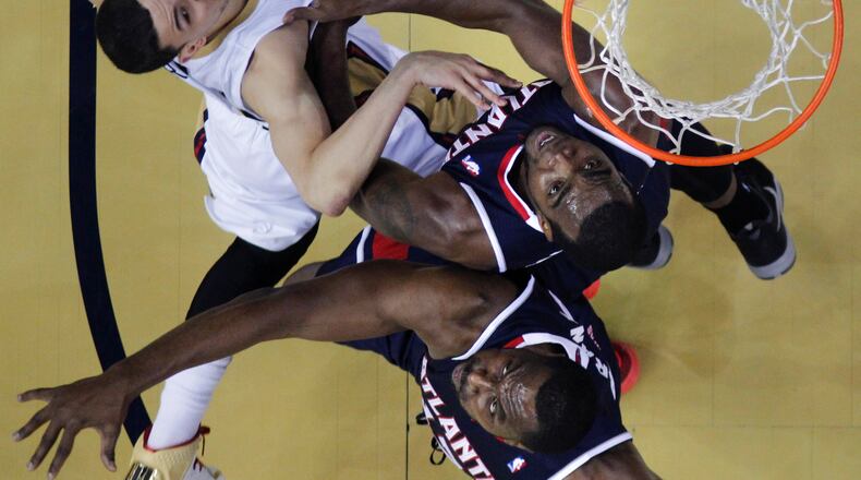 New Orleans Pelicans shooting guard Austin Rivers, left, goes to the basket against Atlanta Hawks power forward Paul Millsap, top right, and power forward Elton Brand in the first half of an NBA basketball game in New Orleans, Wednesday, Feb. 5, 2014. The Pelicans won, 105-100. (AP Photo/Gerald Herbert)
