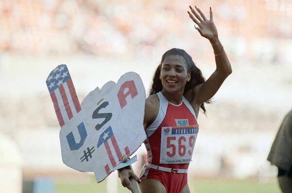 FILE - Florence Griffith Joyner of Los Angeles, Calif., waves to spectators as she holds aloft a U.S.A No. 1 sign following her world record performance in the finals of the women's 200 meters race, Thursday, Sept. 29, 1988, Seoul, Korea. (AP Photo/Lennox McLendon, File)