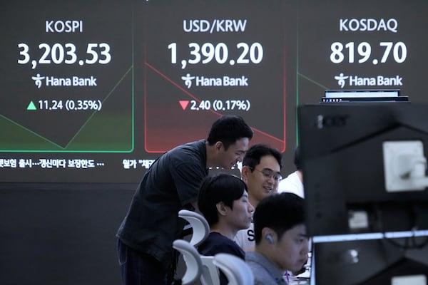 Currency traders work near a screen showing the Korea Composite Stock Price Index (KOSPI), top left, and the foreign exchange rate between U.S. dollar and South Korean won, top center, at the foreign exchange dealing room of the Hana Bank headquarters in Seoul, South Korea, Friday, July 18, 2025. (AP Photo/Ahn Young-joon)