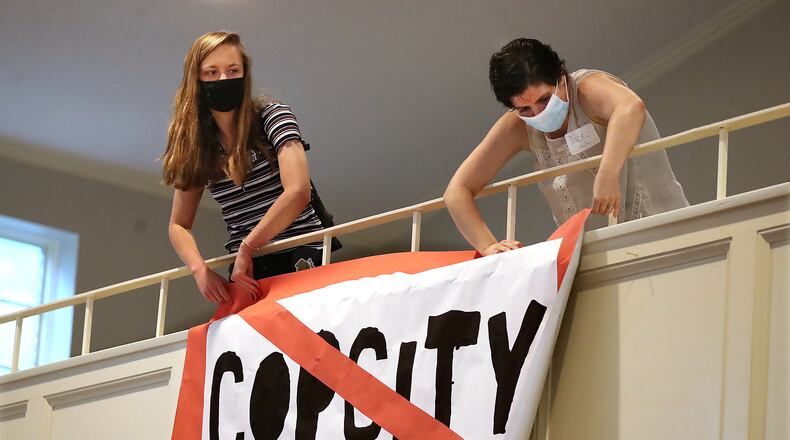 080521 Atlanta: Local activists Kelsea (left) and Nora (right), who go by first names only, hang a "Stop Cop City" banner from the balcony of the Neighborhood Church during a town hall meeting to gather public input in opposition to the plans for a new police and fire training facility in DeKalb County on Thursday, August 5, 2021, in Atlanta.   “Curtis Compton / Curtis.Compton@ajc.com”