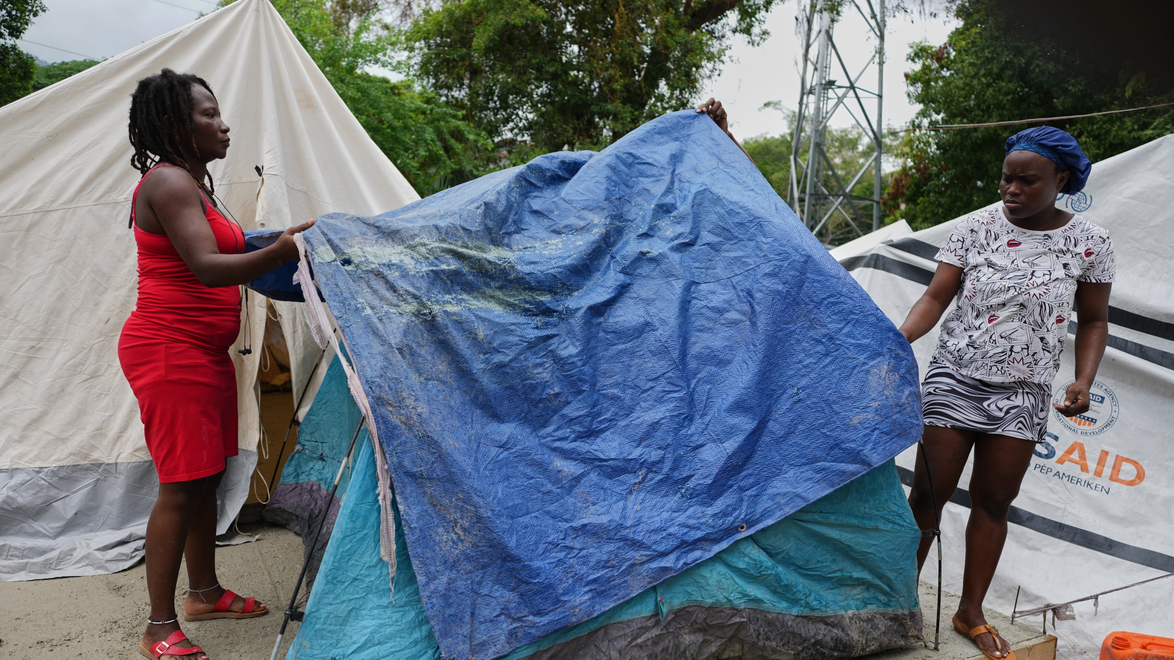 People place plastic tarps over their tents ahead of expected rain at a shelter for families displaced by gang violence in Port-au-Prince, Haiti, Thursday, Oct. 23, 2025. (AP Photo/Odelyn Joseph)