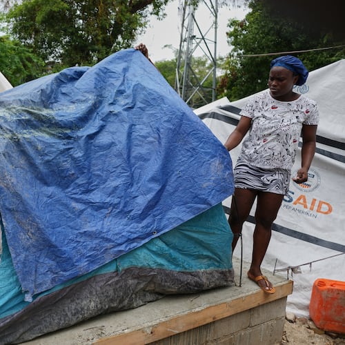 People place plastic tarps over their tents ahead of expected rain at a shelter for families displaced by gang violence in Port-au-Prince, Haiti, Thursday, Oct. 23, 2025. (AP Photo/Odelyn Joseph)