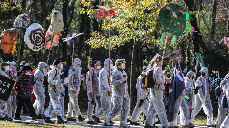 Protesters head through the neighborhoods to the showdown with police on Constitution Road on Nov. 13. After a weekend of protest training, opponents of Atlanta's public safety training center began marching Monday morning from Gresham Park Recreation Center to the site where the $90 million facility is under construction in what organizers are calling a non-violent 'Day of Action.' A few hundred people participated in the march, most wearing masks and many donned in plastic painters suits. City officials say the new center is necessary to provide world-class training to its officers and firefighters, which are currently using outdated facilities. Opponents say it will be used to further militarize police and construction will destroy swaths of one of the largest urban forests in the country. (John Spink / John.Spink@ajc.com)