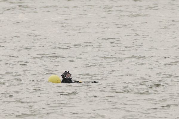 A New York Police Department scuba team diver prepares to search underwater, Friday, April 11, 2025, at the site where a sightseeing helicopter crashed a day earlier into the Hudson River in Jersey City, N.J. (AP Photo/Yuki Iwamura)