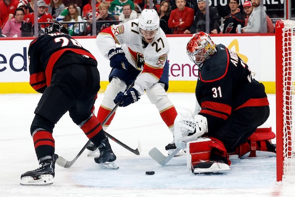 Florida Panthers' Eetu Luostarinen (27) looses control of the puck skating between Carolina Hurricanes' Sean Walker (26) and goaltender Frederik Andersen (31) during the first period of Game 2 of the NHL hockey Stanley Cup Eastern Conference finals in Raleigh, N.C., Thursday, May 22, 2025. (AP Photo/Karl DeBlaker)