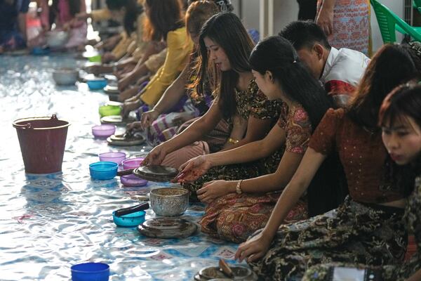 Myanmar's Rakhine ethnic women make sandalwood liquid to make fragrant water as they prepare to doze the fragrant water on Buddha images during the first day of annual traditional water festival also known as "Thingyan", in Yangon, Myanmar, Sunday, April 13, 2025. (AP Photo/Thein Zaw)