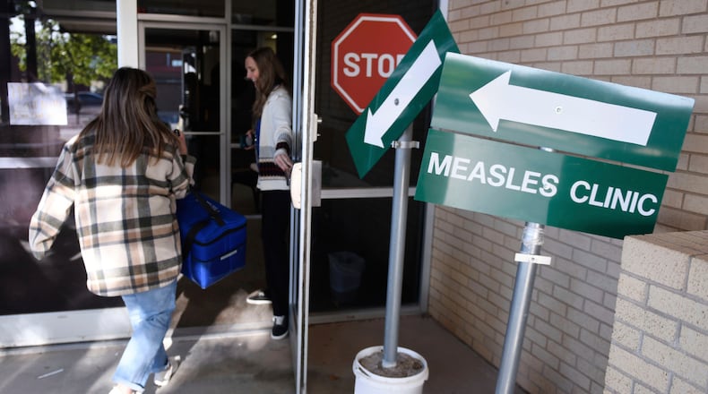FILE - Health department staff members enter the Andrews County Health Department measles clinic carrying doses of the measles, mumps and rubella vaccine, April 8, 2025, in Andrews, Texas. (AP Photo/Annie Rice, File)
