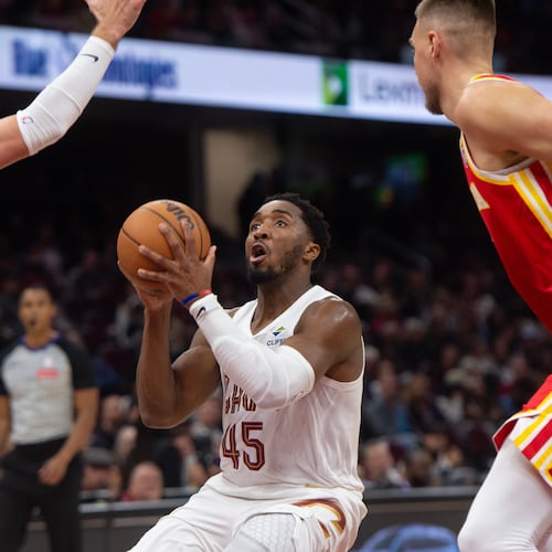 Cleveland Cavaliers' Donovan Mitchell (45) looks to shoot between Atlanta Hawks' Luke Kennard (3) and Kristaps Porzingis, right, during the first half of an NBA basketball game in Cleveland, Sunday, Nov. 2, 2025. (AP Photo/Phil Long)