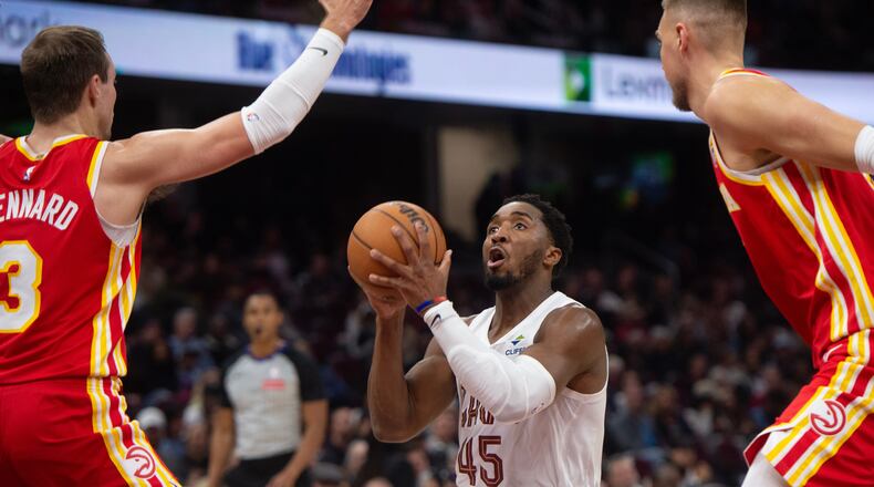 Cleveland Cavaliers' Donovan Mitchell (45) looks to shoot between Atlanta Hawks' Luke Kennard (3) and Kristaps Porzingis, right, during the first half of an NBA basketball game in Cleveland, Sunday, Nov. 2, 2025. (AP Photo/Phil Long)