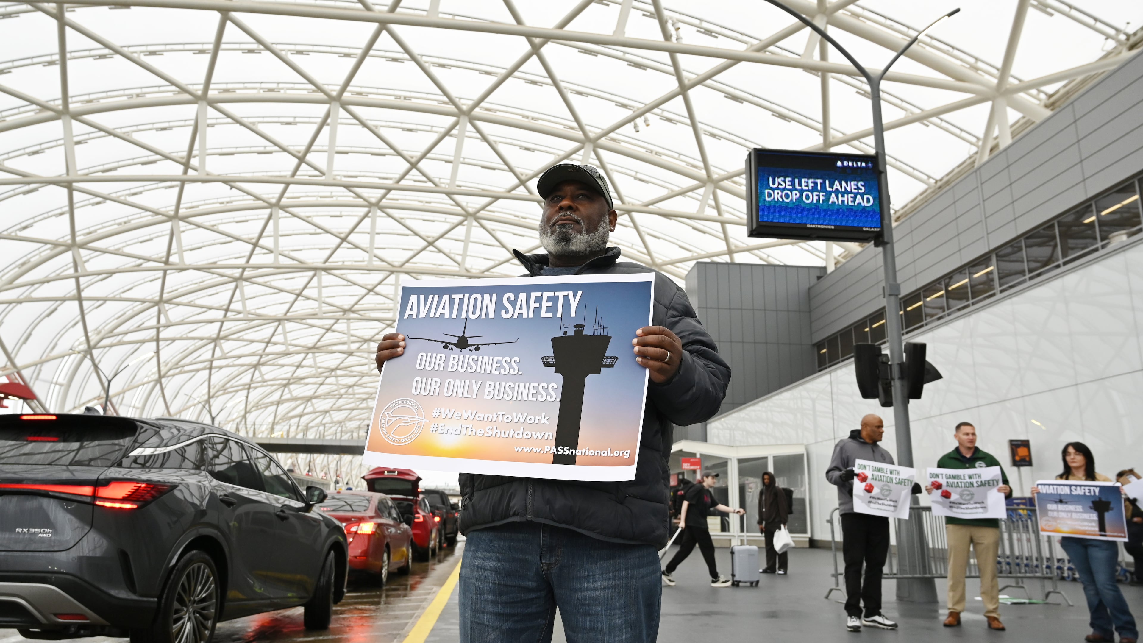 John Love holds a sign with other union members of the Professional Aviation Safety Specialists union at Hartsfield-Jackson Atlanta International Airport's domestic terminal, Wednesday, October 29, 2025, in Atlanta. PASS members at the Federal Aviation Administration (FAA), working without pay or furloughed, held an informational picket at Hartsfield-Jackson to call public attention to the impact of the government shutdown on aviation safety and the personal toll it is taking on their families. (Hyosub Shin/AJC)