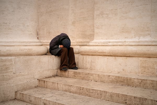 A woman sits in St. Peter's Square as people wait to pay their respects to the late Pope Francis, who will lie in state at St. Peter's Basilica for three days, at the Vatican, Wednesday, April 23, 2025. (AP Photo/Andreea Alexandru)