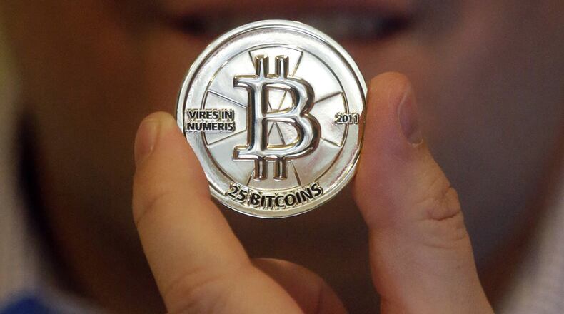 In this April 3, 2013 photo, Mike Caldwell, a 35-year-old software engineer, holds a 25 Bitcoin token at his shop in Sandy, Utah. Caldwell mints physical versions of bitcoins, cranking out homemade tokens with codes protected by tamper-proof holographic seals, a retro-futuristic kind of prepaid cash. With up to 70,000 transactions each day over the past month, bitcoins have been propelled from the world of Internet oddities to the cusp of mainstream use, a remarkable breakthrough for a currency which made its online debut only four years ago. (AP Photo/Rick Bowmer)