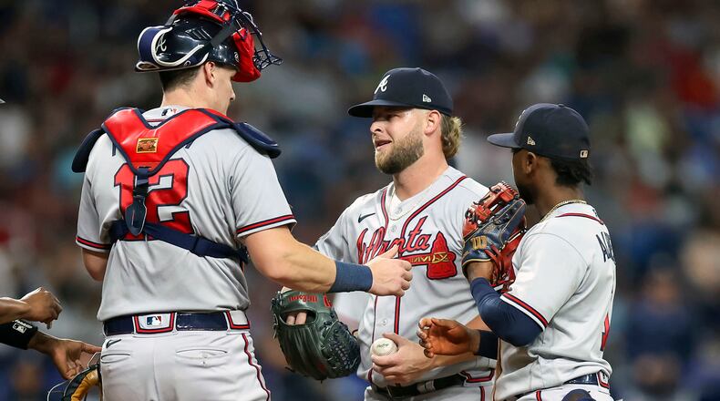Atlanta Braves relief pitcher A.J. Minter, center, is attended to by catcher Sean Murphy (12) and Ozzie Albies, right. before being removed during the eighth inning of a baseball game against the Tampa Bay Rays, Saturday, July 8, 2023, in St. Petersburg, Fla. (AP Photo/Mike Carlson)
