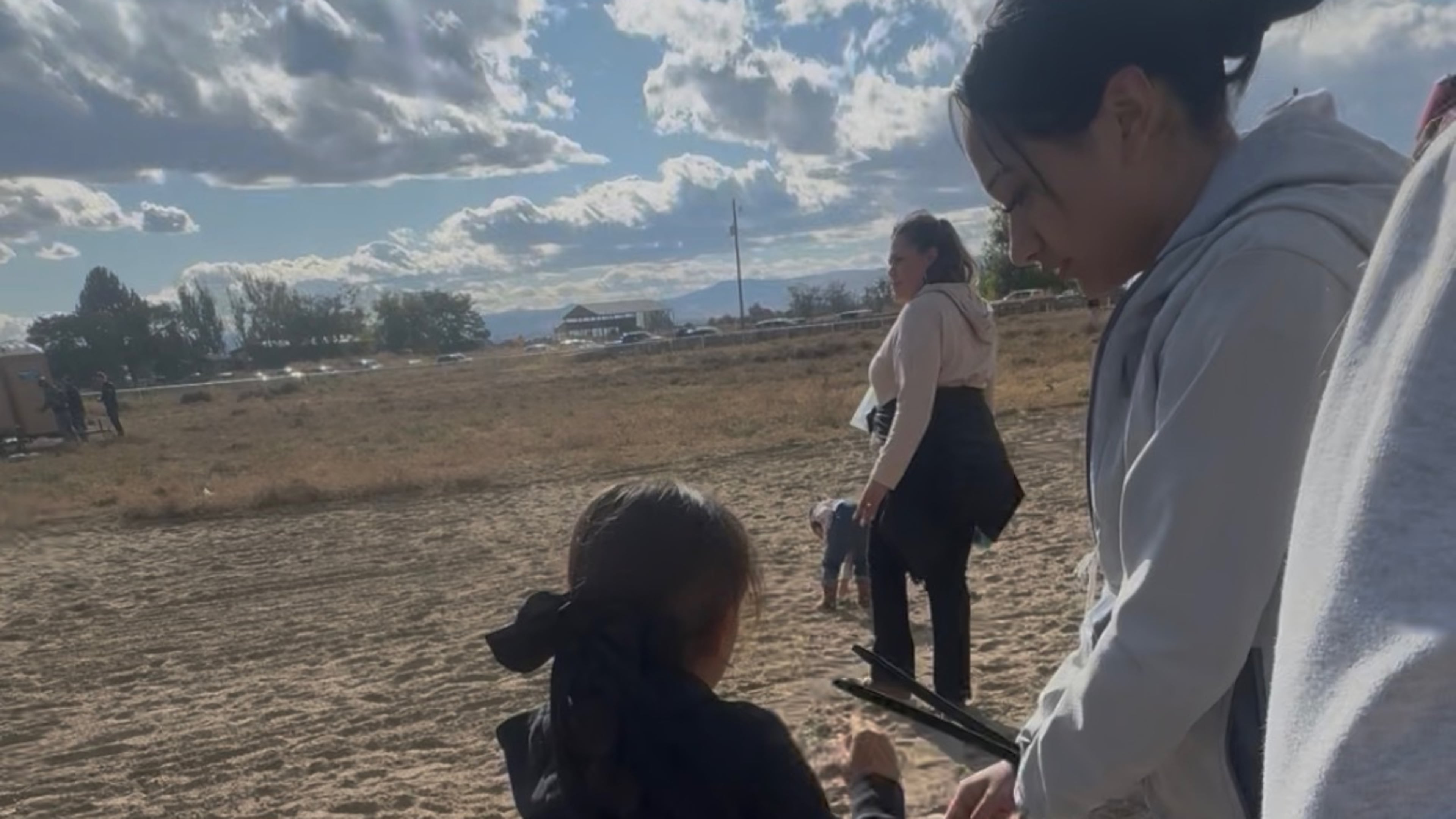 This photo provided by Anabel Romero shows her 14-year-old daughter, right, with her hands zip-tied, next to her 8-year-old daughter, foreground center, during a raid by various law enforcement agencies at La Catedral Arena horse race track in Wilder, Idaho, on Oct. 19, 2025. (Anabel Romero via AP)