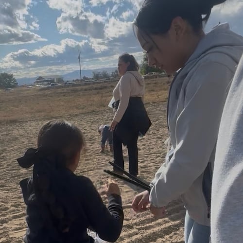 This photo provided by Anabel Romero shows her 14-year-old daughter, right, with her hands zip-tied, next to her 8-year-old daughter, foreground center, during a raid by various law enforcement agencies at La Catedral Arena horse race track in Wilder, Idaho, on Oct. 19, 2025. (Anabel Romero via AP)