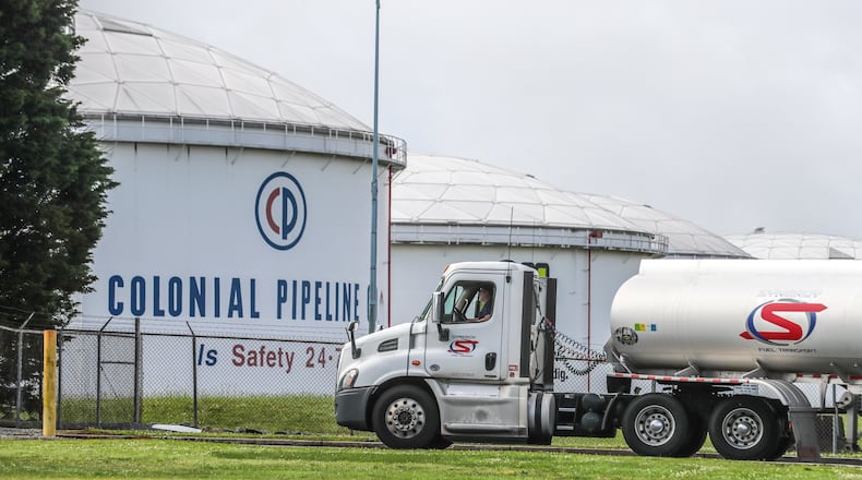 Gasoline tankers pass by the Colonial Pipeline storage tanks in Austell, Georgia on Monday. A ransomware attack has shut down the Alpharetta-based, Colonial's major pipelines that delivers roughly 45% of gasoline and other fuel consumed on the East Coast. Colonial had at least two key security leadership positions unfilled in the weeks before it announced the attack, including one to manage its cybersecurity efforts. (John Spink / John.Spink@ajc.com)