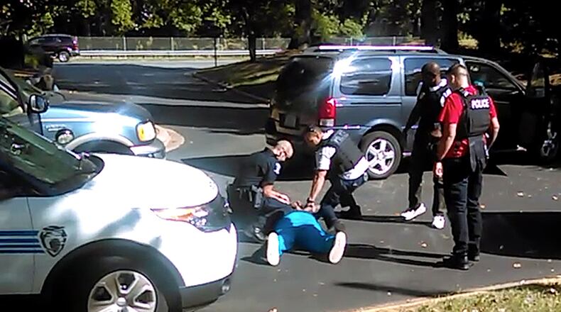 In this image taken from video recorded by Keith Lamont Scott's wife, Rakeyia Scott, on Tuesday, Sept. 20, 2016, Charlotte police squat next to Keith Lamont Scott as Scott lies face-down on the ground, in Charlotte, N.C. In the video of the deadly encounter between Charlotte police and the black man, Rakeyia Scott repeatedly tells officers her husband is not armed and pleads with them not to shoot him as they shout at him to drop a gun. The video does not show clearly whether Scott had a gun. (Rakeyia Scott/Curry Law Firm via AP)