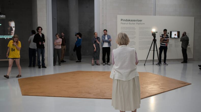 In this photo provided by Niels van der Pas, people look at the peanut butter floor spread across a museum floor in tribute to Dutch artist Wim T. Schippers, who died last month, in Rotterdam, the Netherlands, Thursday, July 9, 2026.(Niels van der Pas/via AP)