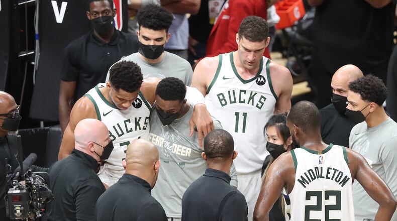 Milwaukee Bucks forward Giannis Antetokounmpo is helped up by his brother Thanasis (right), who also plays for the team, after he hyperextended his left knee. (Curtis Compton / Curtis.Compton@ajc.com)