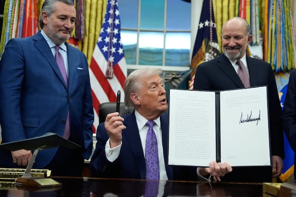 Flanked by U.S. Sen. Ted Cruz (left) and Secretary of Commerce Howard Lutnick, President Donald Trump displays his signed AI initiative in the Oval Office on Thursday. ( Alex Brandon/AP)