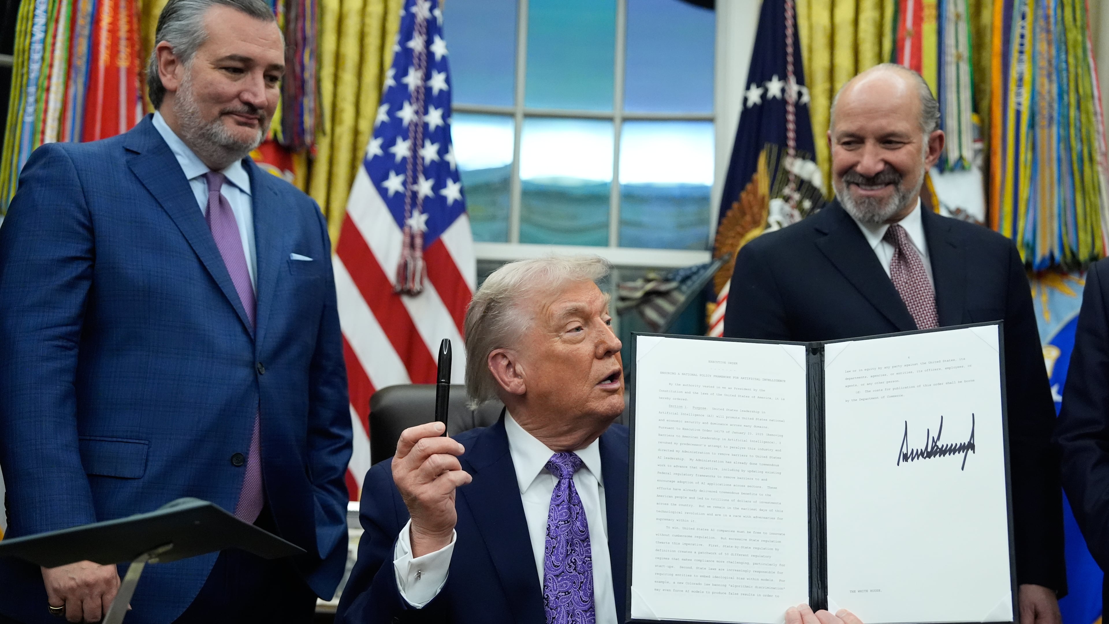 Flanked by Sen. Ted Cruz R-Texas, left, and Secretary of Commerce Howard Lutnick, President Donald Trump displays his signed AI initiative in the Oval Office of the White House, Thursday, Dec. 11, 2025, in Washington. (AP Photo/Alex Brandon)