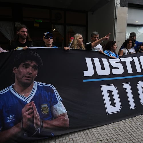 Fans of the late soccer star Diego Maradona stand outside court on the first day of the trial of his medical team for alleged homicide by negligence in San Isidro, Argentina, Tuesday, April 14, 2026. (AP Photo/Rodrigo Abd)