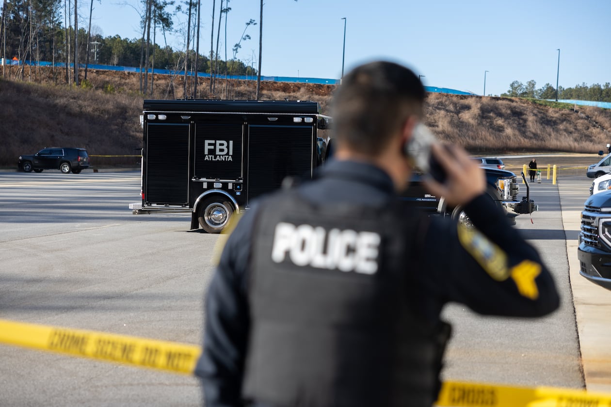 A police officer keeps guard in front of crime scene tape as the FBI conducts a raid on the Fulton County Election Hub and Operation Center in Union City on Wednesday, Jan. 28, 2026. (Arvin Temkar/AJC)